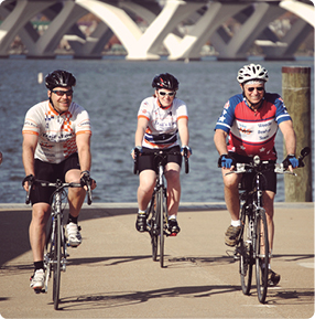 three people biking alongside a river